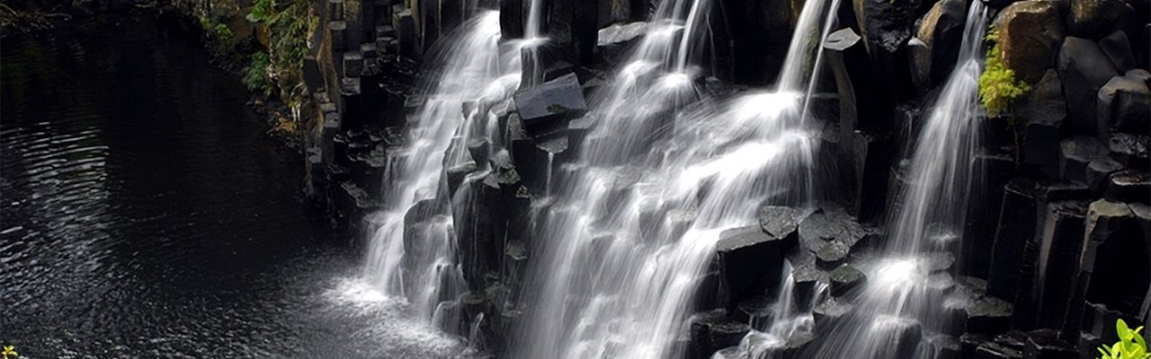 Waterfall near lush green hills